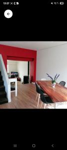 a dining room with a table and a red wall at La voyageuse in Leuhan
