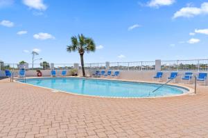 a swimming pool with blue chairs and a palm tree at SeaSpray Riverside 312 in Perdido Key