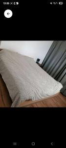 a bed with a gray pillow on a wooden floor at La voyageuse in Leuhan