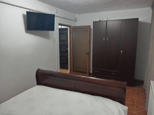 ein Schlafzimmer mit einem Bett und einem Holzschrank in der Unterkunft imocris in Fălticeni