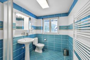 a blue tiled bathroom with a toilet and a sink at Hotel Resort Martin & Kristyna in Špindlerův Mlýn +105 photos