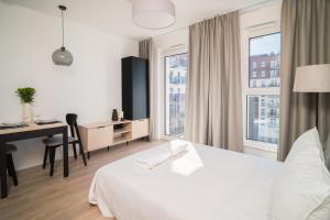 a hotel room with a bed and a desk and window at Prime Apartments Gdańsk in Gdańsk