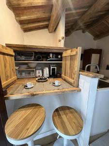 a kitchen with a counter with two wooden stools at La casina del borgo - Monolocale Nettuno in Perugia +48 photos