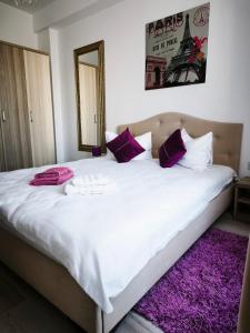 a bedroom with a large white bed with purple pillows at SeaLaVie - Summerland Mamaia in Mamaia