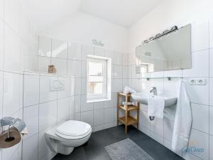 a white bathroom with a toilet and a sink at Hus Krüüzpadd boben in Cuxhaven +16 photos