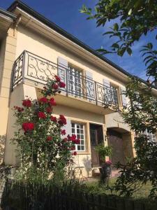 a white house with a balcony and red flowers at Clos Belin in Chavornay