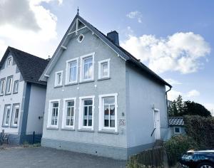 a white house with white windows and a car at Hus Krüüzpadd boben in Cuxhaven