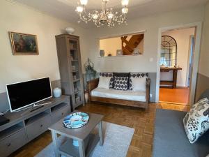 a living room with a couch and a tv at Clos Belin in Chavornay