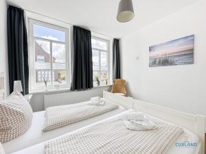 two beds in a bedroom with two windows at Hus Krüüzpadd unnen in Cuxhaven