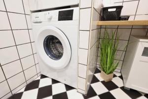 a washing machine in a bathroom with a green plant at St Antoni Suite 4 in Eisenstadt
