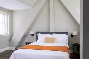 a bedroom with a white bed with an orange blanket at Downtown Luxury 1BR Loft · Walkable · Sleeps 4 in Milwaukee
