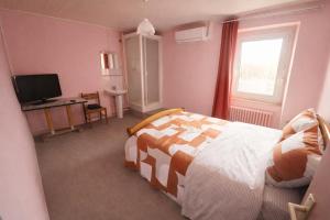 ein Schlafzimmer mit Bett, Schreibtisch und Fernseher in der Unterkunft The Val Hotel in Châlus