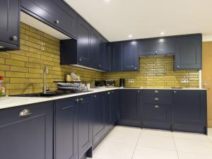 a kitchen with blue cabinets and a brick wall at Beautiful River View with Sauna in Llandysul