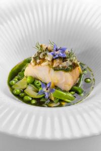a plate of food with fish and peas and purple flowers at La Chartreuse du Bignac - Teritoria in Saint-Nexans +68 photos