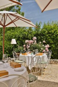 a table with chairs and an umbrella and flowers at La Chartreuse du Bignac - Teritoria in Saint-Nexans