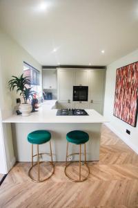 a kitchen with two green bar stools in front of a counter at Unique 3 Bed Home, Stewarton in Stewarton