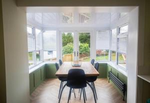 a dining room with a table and chairs and windows at Unique 3 Bed Home, Stewarton in Stewarton +21 photos