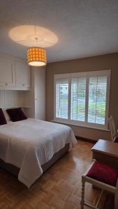 a bedroom with a bed and a table and windows at Crossriver B&B in Oughterard