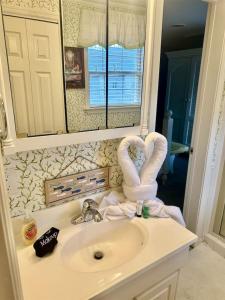 a bathroom with a sink with a towel swan on it at Just Peachy in Myrtle Beach +34 photos