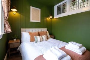 a green bedroom with a bed with towels on it at Unique 1 Bed Apartment, Auchterarder in Auchterarder