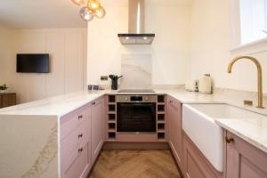 a kitchen with white counters and a sink and a stove at Unique 1 Bed Apartment, Auchterarder in Auchterarder