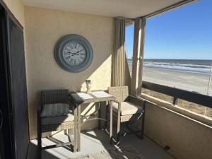 a table with chairs and a clock on a balcony at Ocean Front Condo-Beach Front Pool Hottub Elevator in Myrtle Beach
