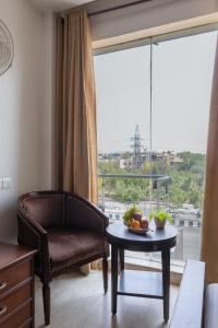 a living room with a chair and a table and a window at Hotel The Imperio, Near Apollo Hospital, JASOLA in New Delhi