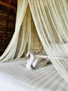 a bed with a canopy with a swan laying on it at Rice Field and Mountain View House in Karangasem