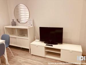 a living room with a tv on a white stand with a mirror at San Gregorio 2 in Soria