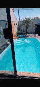 a view of a swimming pool through a window at Casa com piscina in Londrina