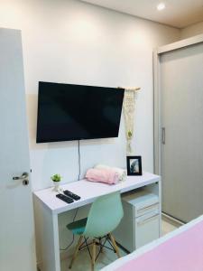 a desk with a monitor on a wall with a chair at Casa com piscina in Londrina