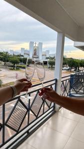 a person holding up wine glasses on a balcony at Apto Centro de Sinop - 720C in Sinop