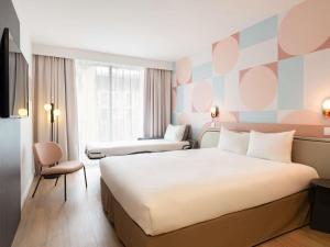 a hotel room with a large bed and a chair at ibis Styles Paris Porte d'Orléans in Montrouge +95 photos
