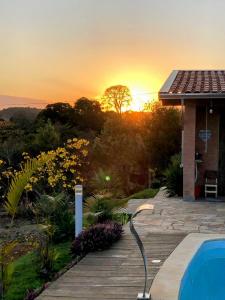 a house with a pool and a sunset in the background at Chácara Por do Sol in Pouso Alegre