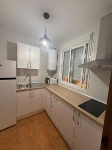 a kitchen with white cabinets and a sink and a window at Alfarnate Antiguo Cuartel in Alfarnate