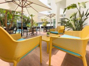 a restaurant with yellow chairs and tables and chairs with an umbrella at Hotel Jaime I in Peniscola