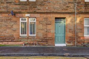 a brick building with a green door and two windows at Tiffanys Boutique - Coorie Doon Stays in Prestwick