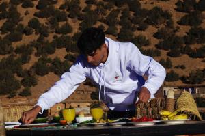 a chef preparing food on a table in front of a buffet at Chez youba in Azilal
