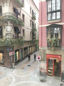 two people walking down a city street with buildings at Pensión AliciaZzz Bed And Breakfast Bilbao in Bilbao