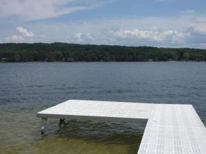 a white dock in the water near a lake at Sandy Bottom Cottage on Intermediate Lake in Bellaire