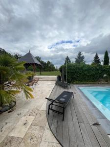 a wooden deck with a bench next to a swimming pool at Le Val Cosy in Montlivault