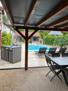 a patio with a table and chairs and a pool at Le Val Cosy in Montlivault