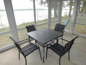 a table and chairs in a porch with a view of the water at South Cottage on Torch Lake in Alden