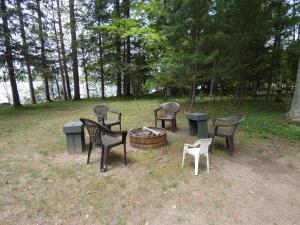 a group of chairs sitting around a fire pit at Lakeside Cottage on Torch Lake in Alden
