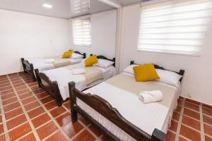 a room with three beds with yellow pillows at El cantor Finca hotel in Quimbaya