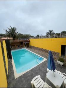 a large swimming pool with two chairs and an umbrella at Refúgio Beira-Mar in Itanhaém