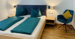 a bedroom with a bed with blue pillows and a chair at Unterlechnerhof in Vollan