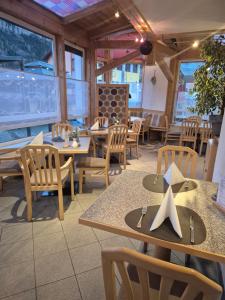 a restaurant with tables and chairs and windows at Hotel Gletschermühle in Flattach