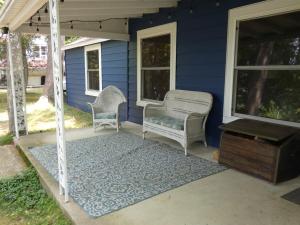 a blue house with two wicker chairs on a porch at Cranberry Cottage on Torch Lake in Alden