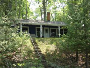 a blue house in the middle of a forest at Cranberry Cottage on Torch Lake in Alden